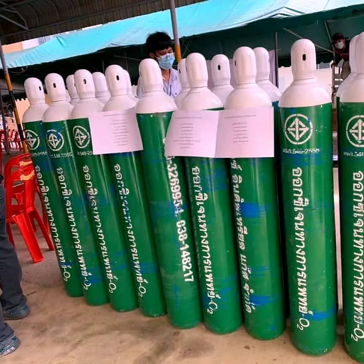 Row of green-and-white oxygen cylinders with labels attached, ready for handover