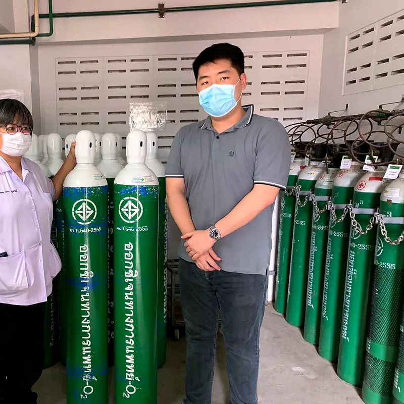Staff standing beside green-and-white oxygen cylinders in a storeroom