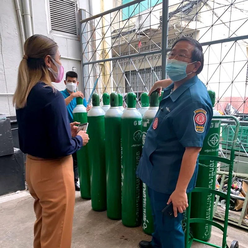 Team members standing beside green oxygen cylinders and a cylinder trolley